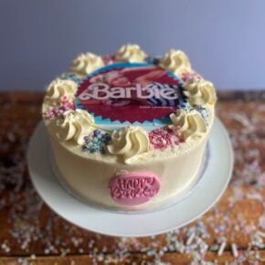 Barbie themed Buttercream birthday Cake with a Barbie picture featuring Margot Robbie, blue and pink sprinkles and a pink Happy Birthday Plaque